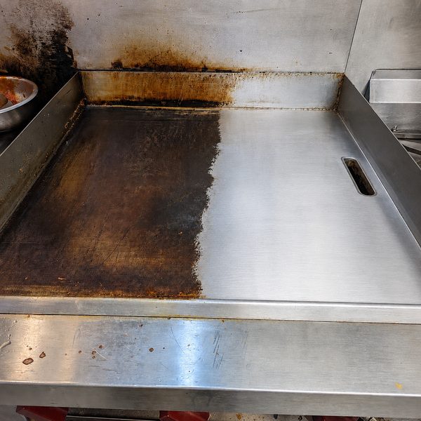 Laser cleaning carbon buildup from stainless steel kitchen equipment